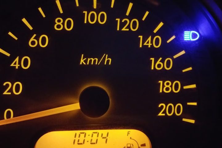 Close-up of an illuminated car speedometer display showing kilometers per hour.